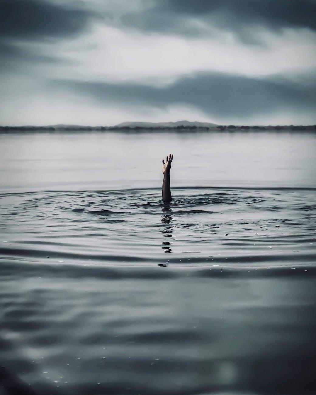 hand reaching out of a person drowning in water