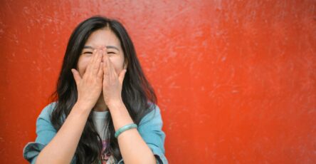 cheerful ethnic woman against vivid red painted wall